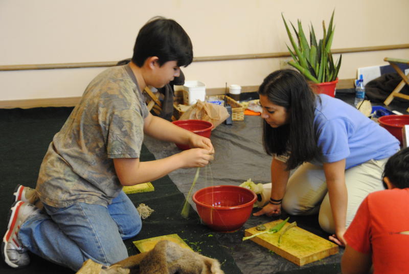 A Witte Museum staff member helps a fair attendee make a piece of cordage out of the Texas native plant Lechugilla.