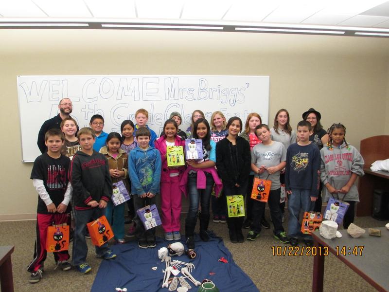Dr Lorenzo (on the left in the back smiling) and Mrs. Briggs' 5th grade class with their Snack Kits in Halloween bags.