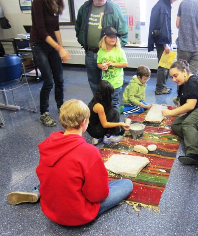 Children learn to grind grain the prehistoric way at the Milwaukee Society Lab open house.