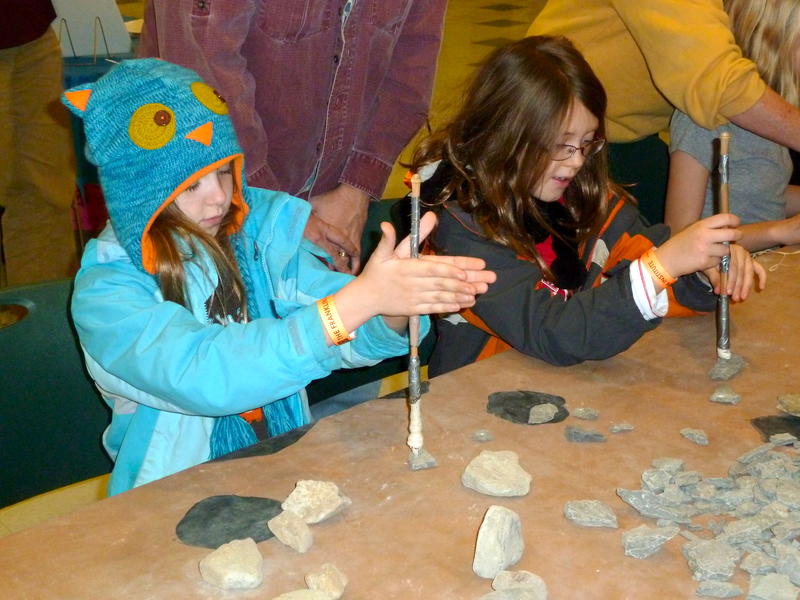 Fair participants use ancient driling techniques to create a stone pendant for their corded necklace.