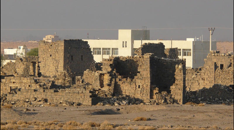 A modern school building behind the ancient ruins of Umm el-Jimal