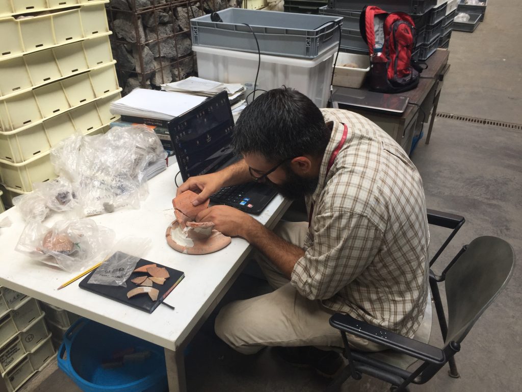 Figure 2: Finds Lab Supervisor Giordano Iacomelli joins fragments of a North African amphora coming from our current excavation below the podium with finds from the 2005 dig underneath the west court of the sanctuary.